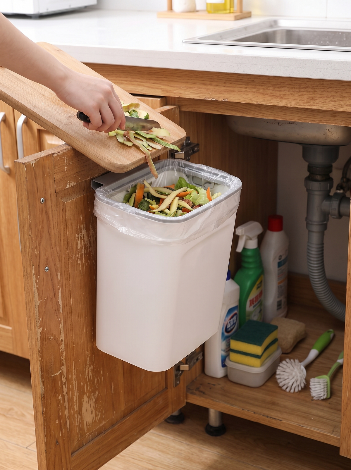 Compost bin hanging inside a sink cupboard door